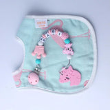 Baby bib with pink teether and decorative elements on a light blue background