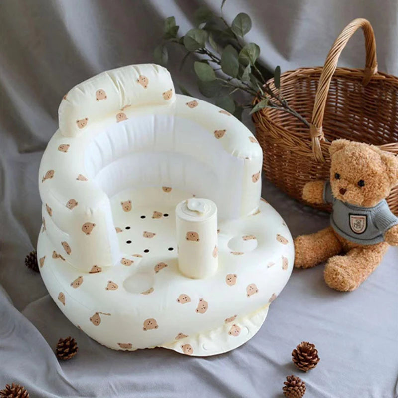 Baby seat with teddy bear pattern next to a teddy bear and basket on a neutral background