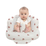 Baby sitting in a white cushion with bear patterns on a white background