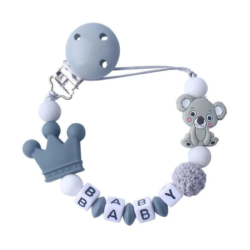 Baby teething toy with crown, koala, and 'BABY' beads on a white background