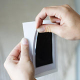 Person holding a small rectangular mirror with a plain background