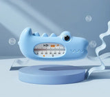 Blue shark-shaped bath thermometer on a light blue platform with bubbles in the background