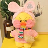 Plush toy duck with pink sweater and glasses on a yellow surface