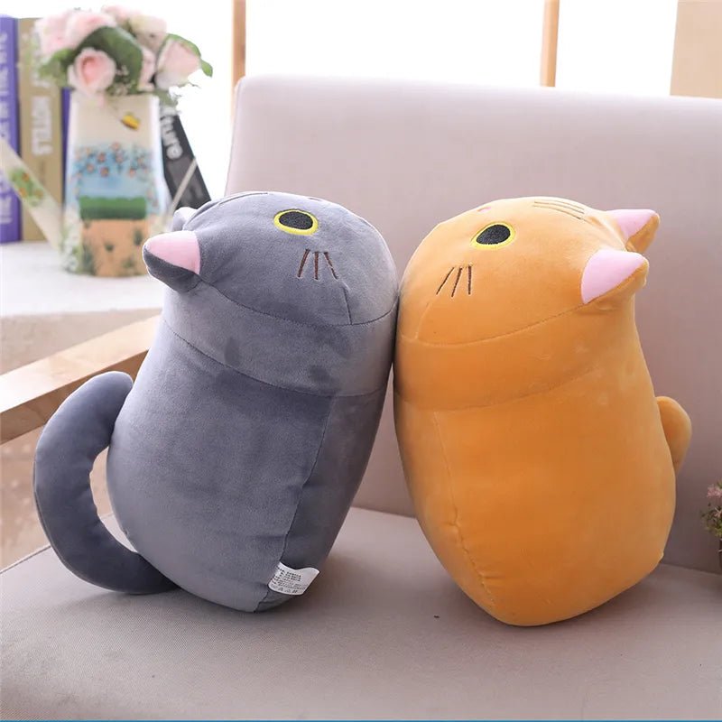 Two plush toys, one gray and one orange, sitting on a couch.