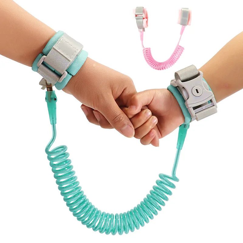 Two children holding hands with a teal safety leash and a pink leash.
