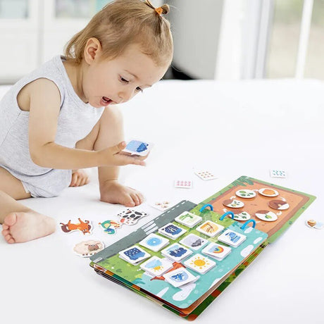 Child playing with a colorful educational book on a white surface