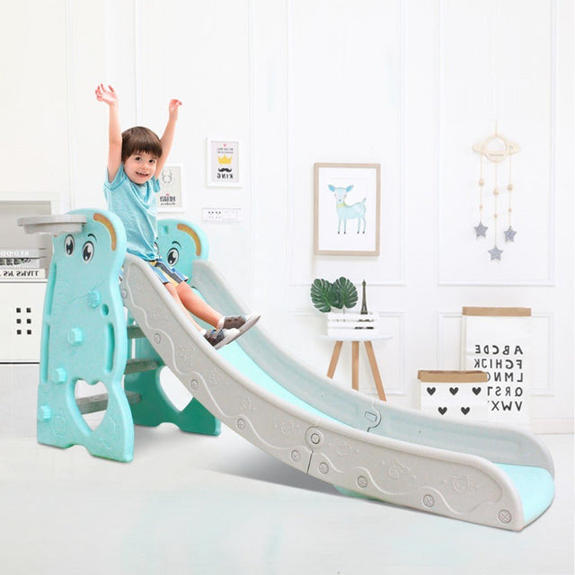 Child sliding down a blue and gray slide in a room with decor elements.