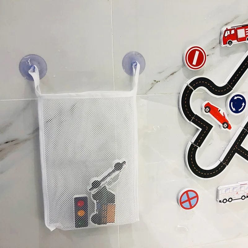 Mesh storage bag with suction cups on a wall, next to toy road and vehicle decorations.