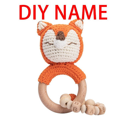 Crocheted fox rattle with wooden ring and beads on a white background