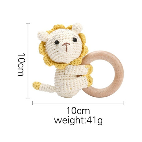 Crocheted lion toy with wooden ring and measurements on a white background