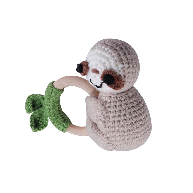 Crocheted sloth toy holding a green leaf on a white background