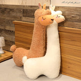 Two plush llamas, one brown and one white, against a wooden wall.