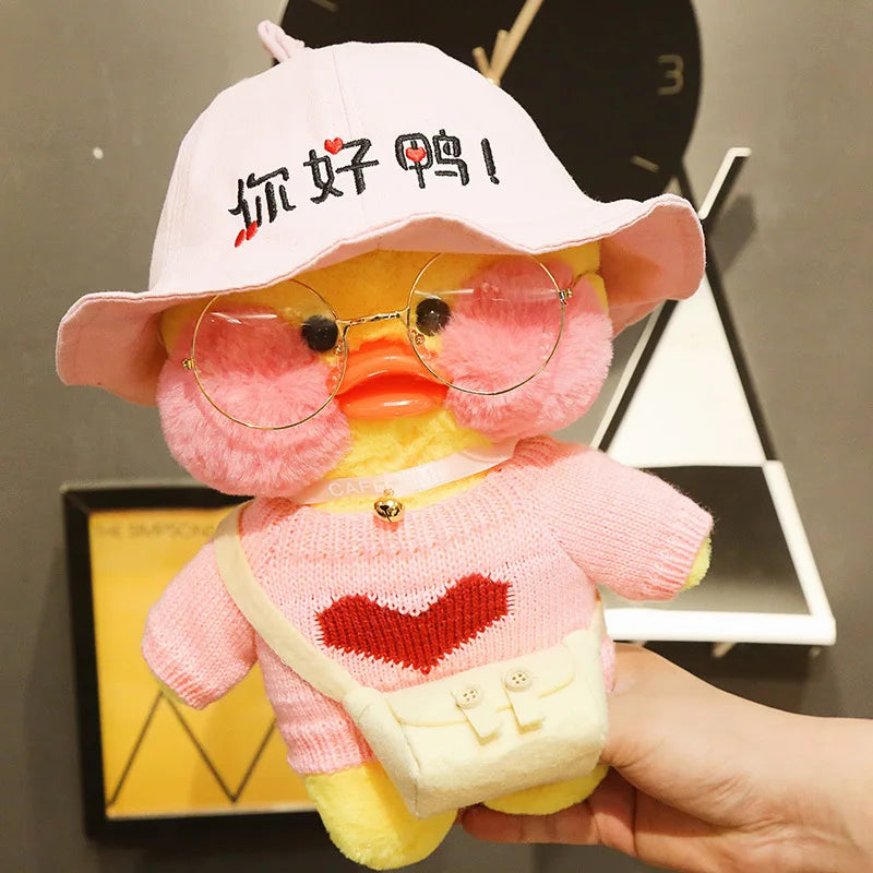 Plush toy duck wearing a pink hat with Chinese text, glasses, and a pink sweater with a red heart on a dark background.
