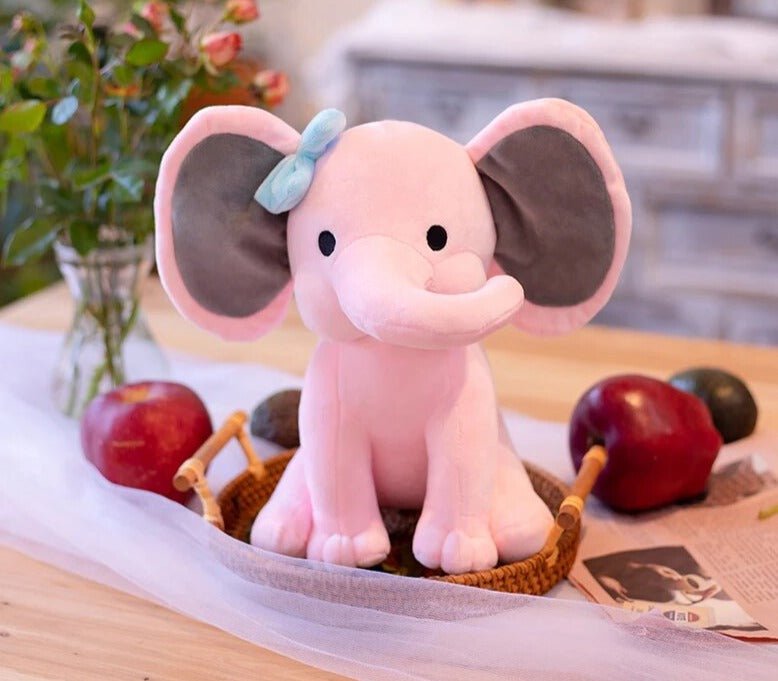 Pink elephant plush toy with a bow on a table.