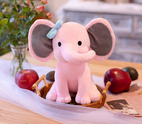 Pink elephant plush toy with a bow on a table.