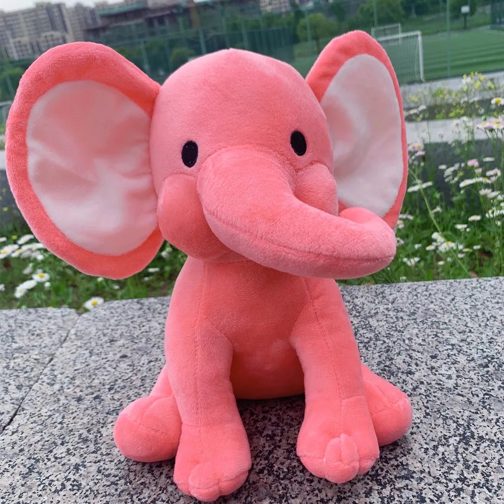 Pink plush elephant toy on a stone surface.