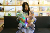 Woman holding two glowing stuffed animals on a couch.