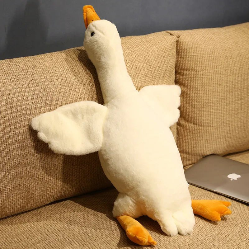 Plush toy goose on a beige couch.