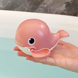 Pink whale-shaped toy held in a hand.