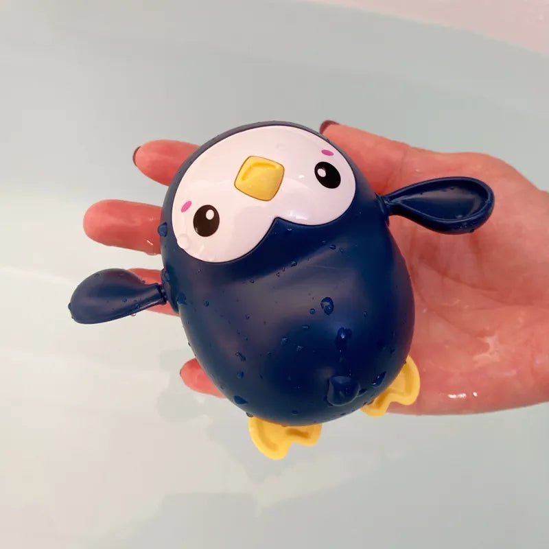 Hand holding a penguin-shaped bath toy.