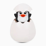 Penguin toy emerging from a white egg.