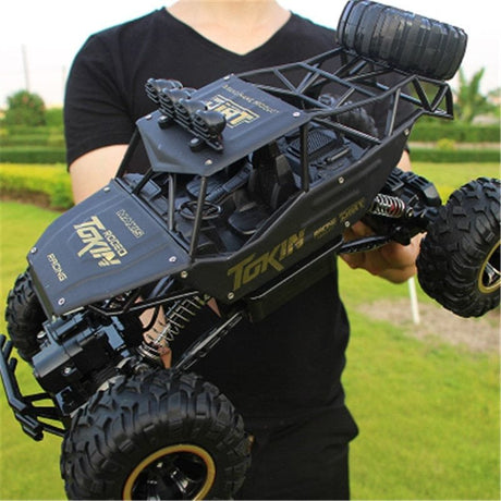 Person holding a large black and yellow RC truck model outdoors