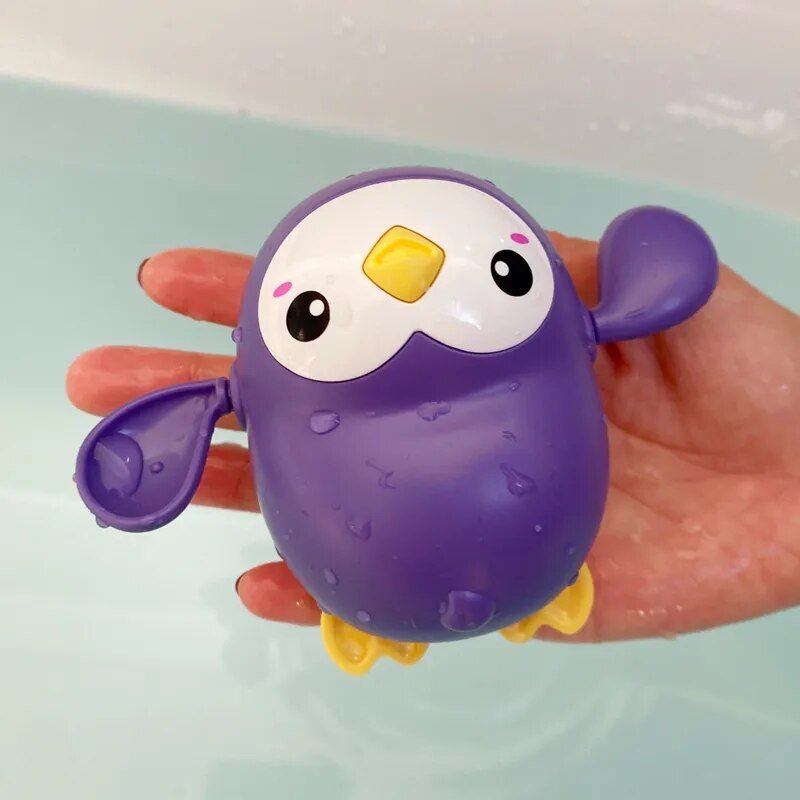 Purple penguin bath toy held in a hand.