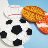 Four pop-it toys shaped like a soccer ball, basketball, baseball, and tennis racket on a blue background.