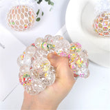 Hand holding a clear gel ball with colorful beads.