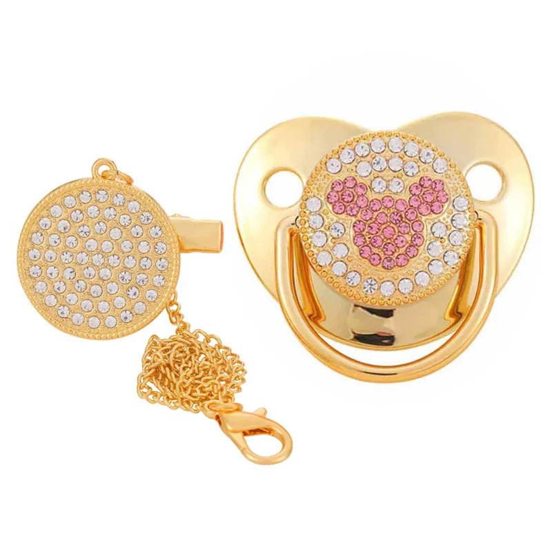 Gold pacifier with pink and white design on a white background