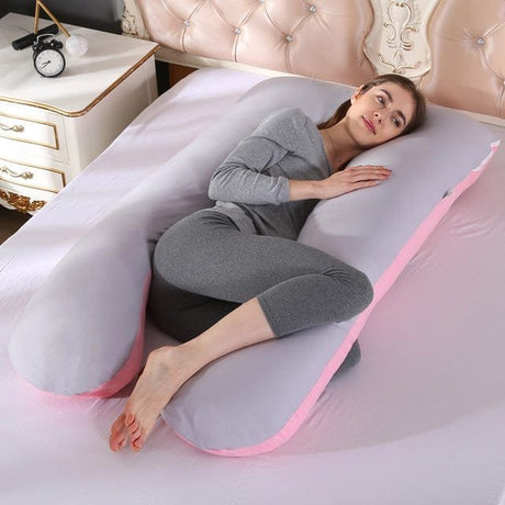 Woman lying on a U-shaped body pillow in a bedroom setting.
