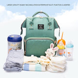 Green backpack with baby care items on a white background