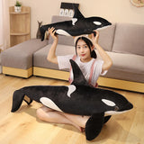 Person holding a large plush orca whale toy in a living room.