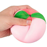 Hand holding a pink and green stress ball against a white background