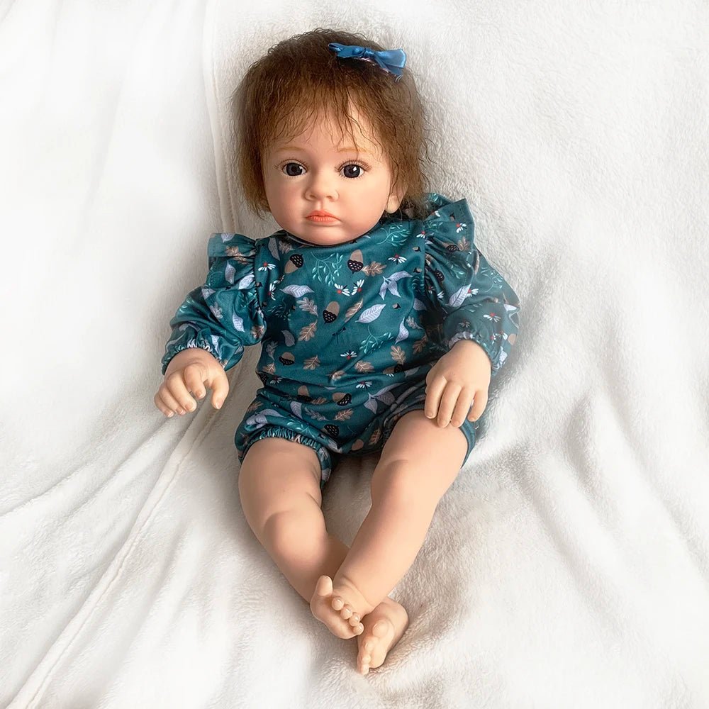 Doll wearing a blue patterned outfit on a white blanket