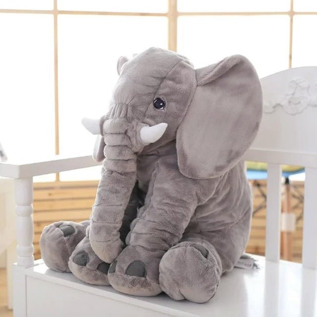 Gray plush elephant toy on a white surface.