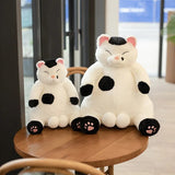 Two plush cat toys with black and white patterns on a wooden table.