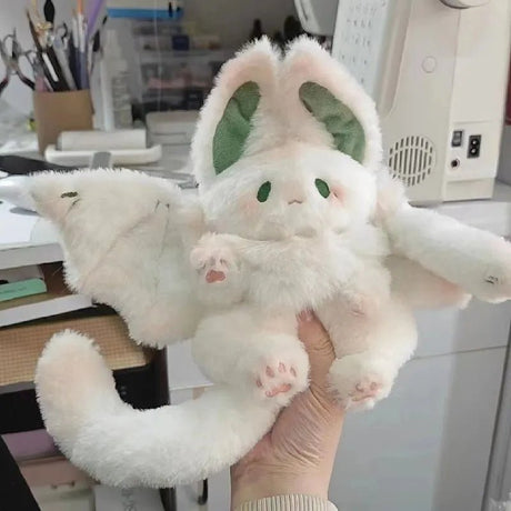 Plush toy resembling a white creature with large ears held in a hand