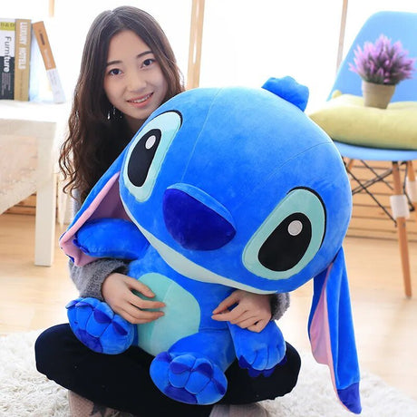 A person holding a large blue plush toy in a room.