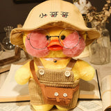Yellow plush toy with glasses and a hat on a table with books and decorative items.