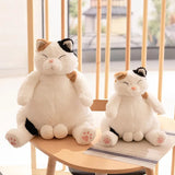 Two plush cat toys sitting on a chair 