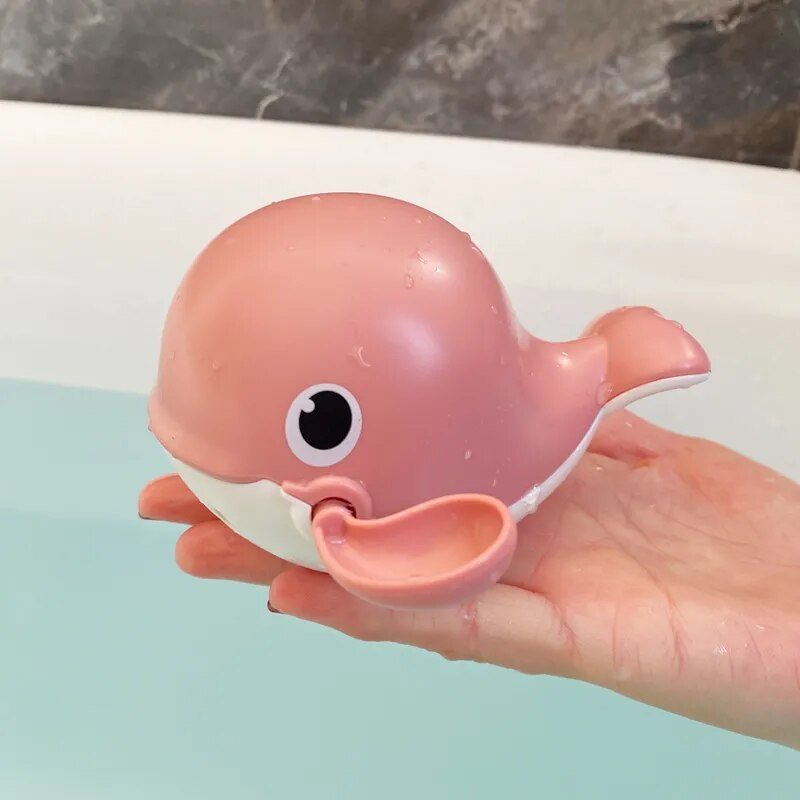 Pink whale-shaped toy held in a hand.
