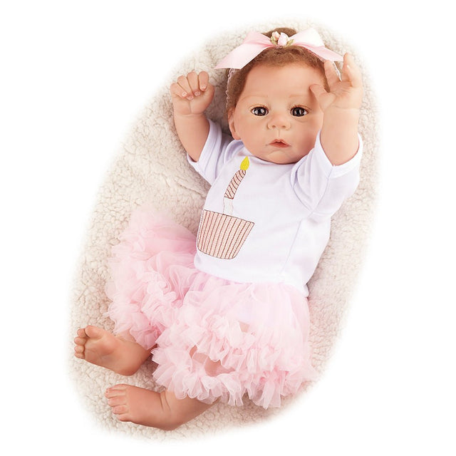 Baby doll in a white outfit with a pink ruffled skirt and a headband.