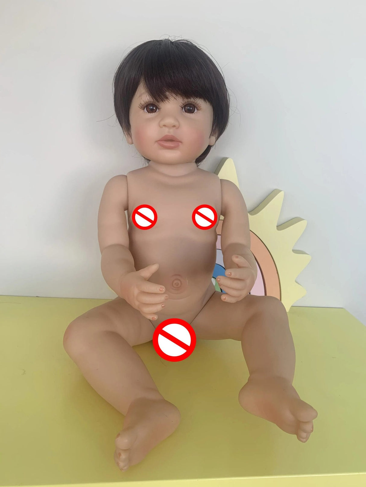 Realistic baby doll with red circles indicating prohibited areas.