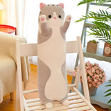 Cat-shaped plush toy on a chair in a room with plants and flowers.