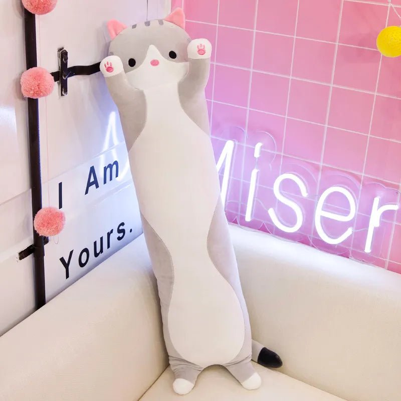 Cute plush toy resembling a cat with pink ears and paws on a couch.
