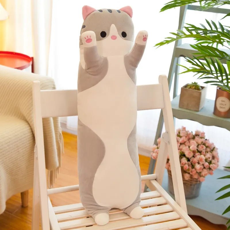 Cat-shaped plush toy on a chair in a room with plants and flowers.