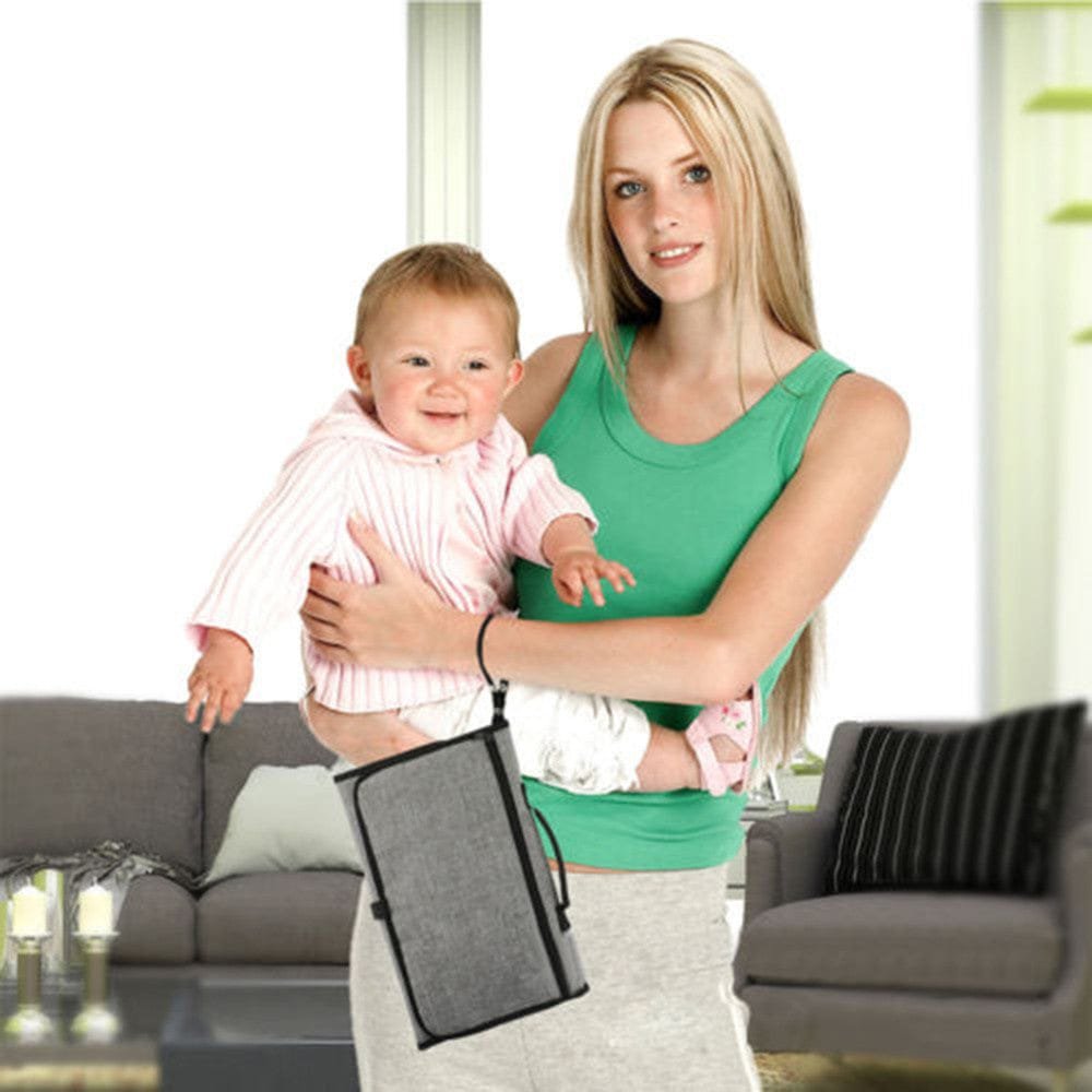 A woman holding a baby and a black diaper changing bag.