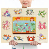 Child holding a wooden puzzle with sea-themed pieces