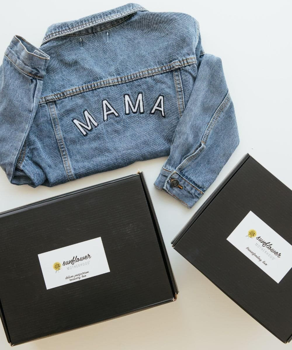 Denim jacket with 'MAMA' embroidery on a white surface with black boxes.
